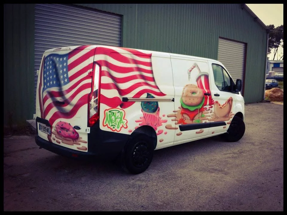 Vue arrière du food truck peint par Más à Seignosse avec drapeau américain et décor street food