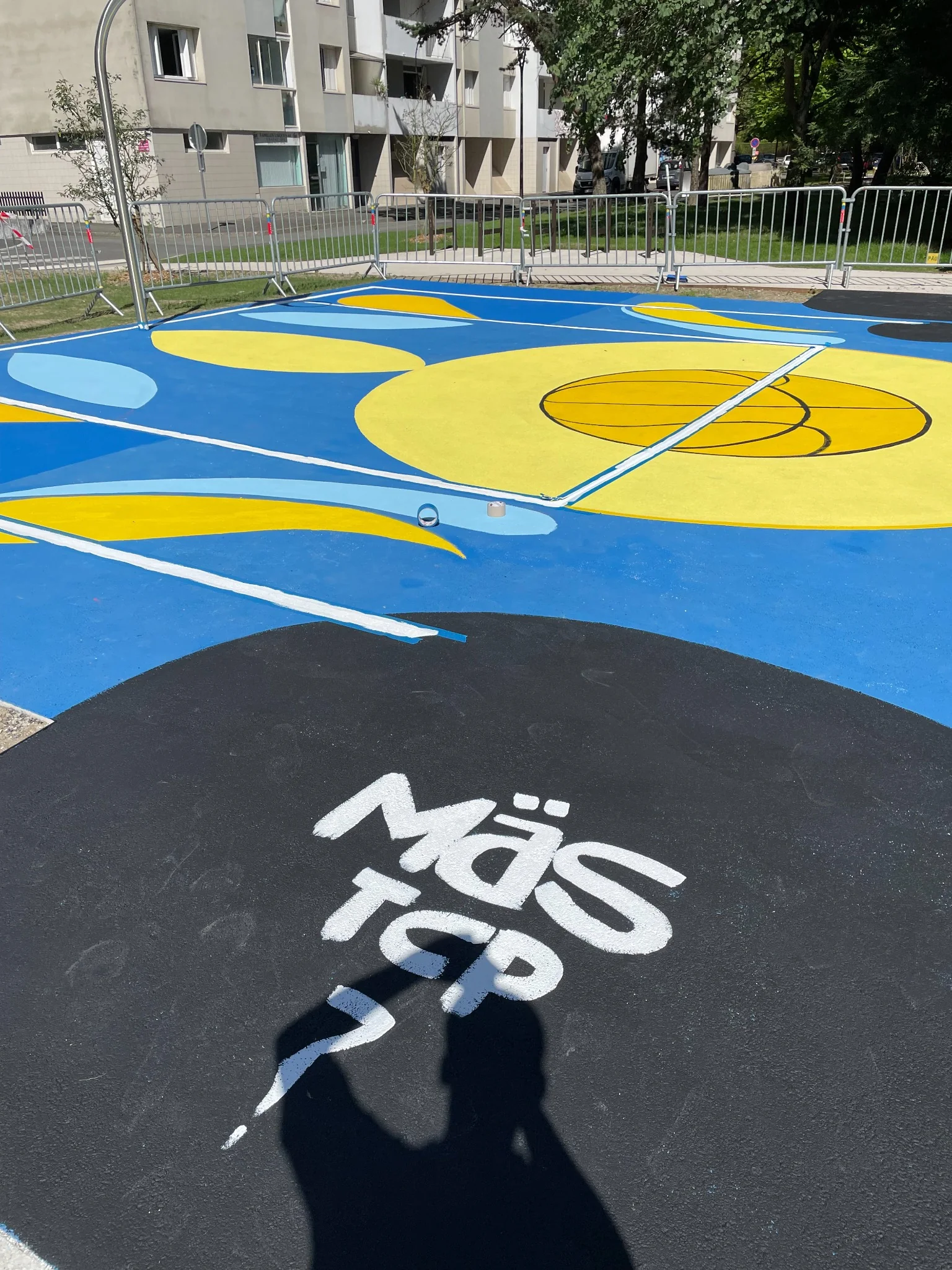 Playground de basket bleu et jaune à Pau, peinture participative réalisée par Más avec des jeunes